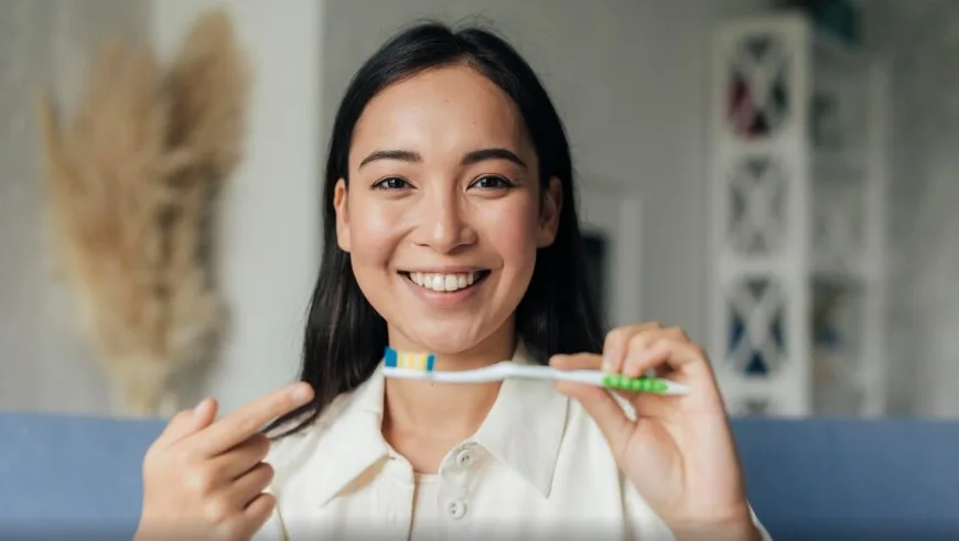 7 Cara Menjaga Kesehatan Gigi dan Mulut Saat Puasa, Yuk Simak! 7 seorang wanita memegang sikat gigi berwarna putih dan hijau untuk meunjukkan cara menjaga kesehatan gigi dan mulut
