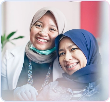 Service Aligner 1 Dokter gigi wanita berjilbab dan pasien wanita berjilbab tersenyum bahagia, pasien memakai behel gigi, menunjukkan hasil perawatan ortodonti yang sukses di Klinik Drg. Adianti.