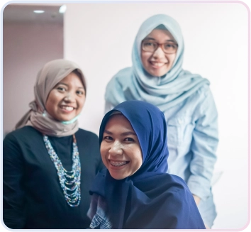 Service Aligner 3 Tiga wanita tersenyum di klinik gigi, salah satunya pasien dengan behel gigi, menunjukkan suasana ramah dan hasil perawatan gigi yang memuaskan.