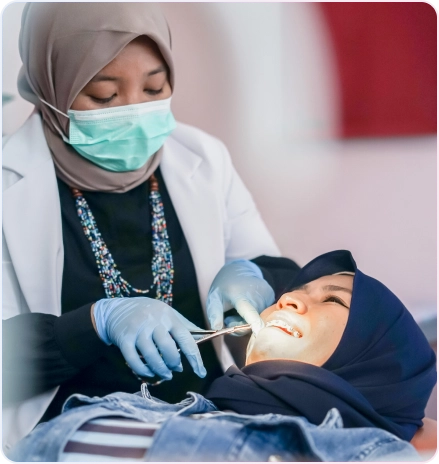 Service Behel 5 Dokter gigi wanita berjilbab dengan masker dan sarung tangan sedang melakukan pemasangan atau penyesuaian behel gigi pada pasien wanita.