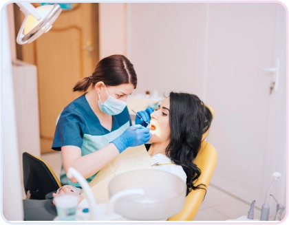 Seorang dokter gigi wanita sedang memeriksa dan merawat gigi pasien wanita di kursi dental klinik gigi.